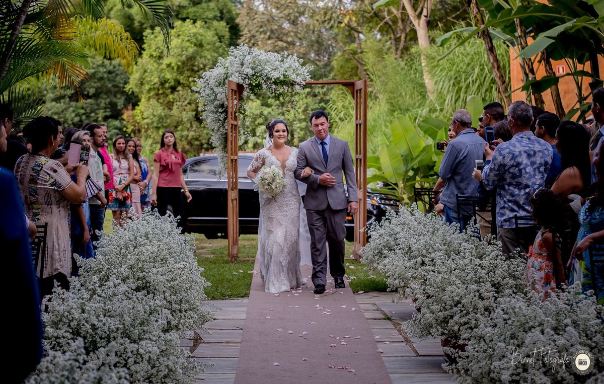 Noiva entrando de braços dados com seu pai e convidados admirados com o momento