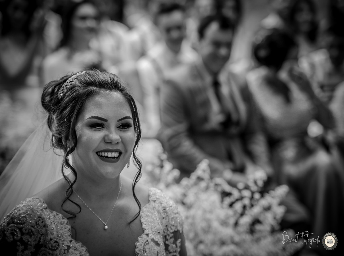 Foto preta e branca do rosto da noiva que está com um grande sorriso expressando a felicidade do momento 