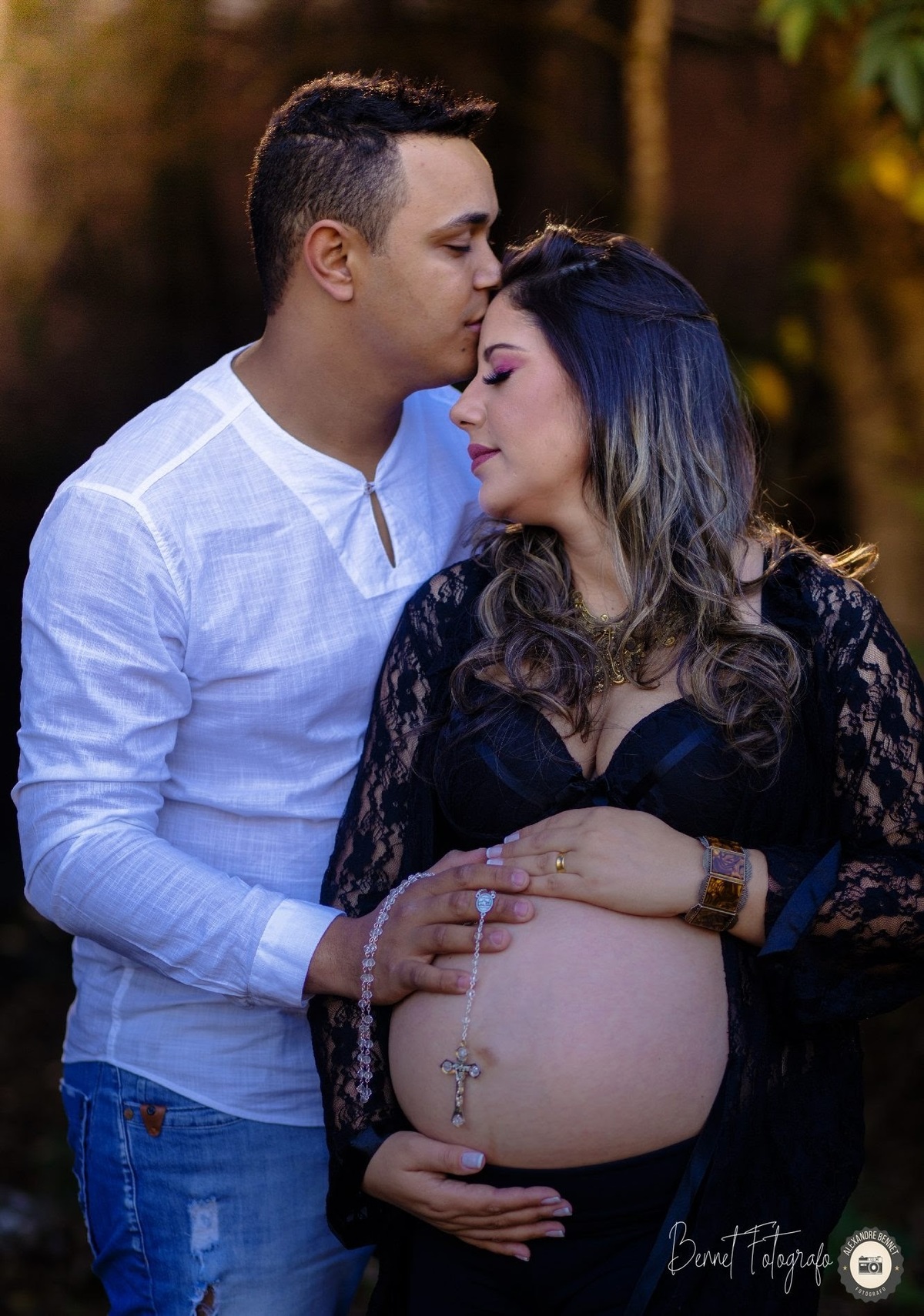 Pai beija testa da mãe enquanto segura um terço em sua barriga 