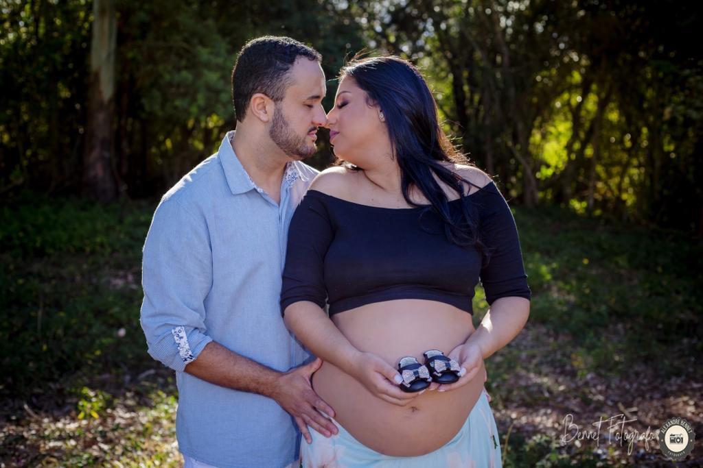 Pais se beijam enquanto mãe segura sapatinhos do bebê 