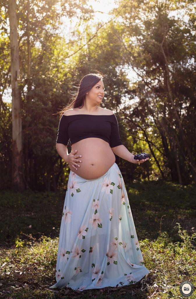 Mãe segura sapatinho do bebê enquanto sorri 