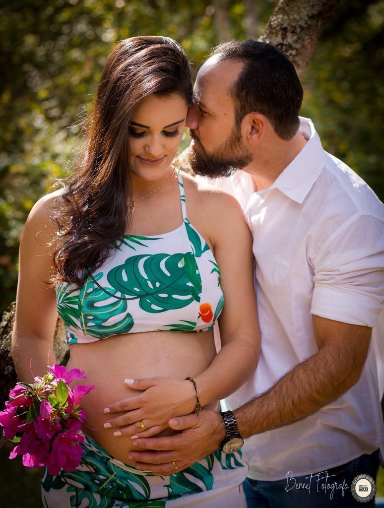 Pai beija mãe enquanto ela olha para barriga 