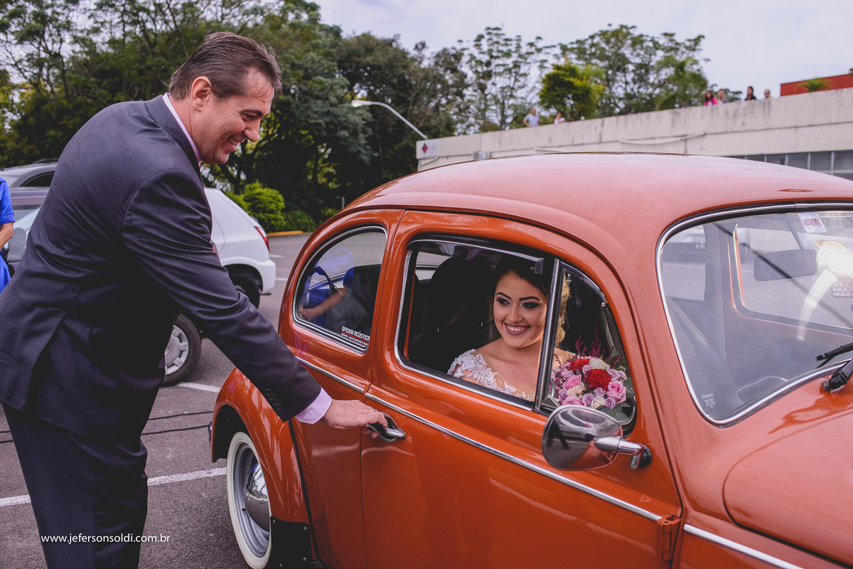 Noiva chegando em um fusca laranja.