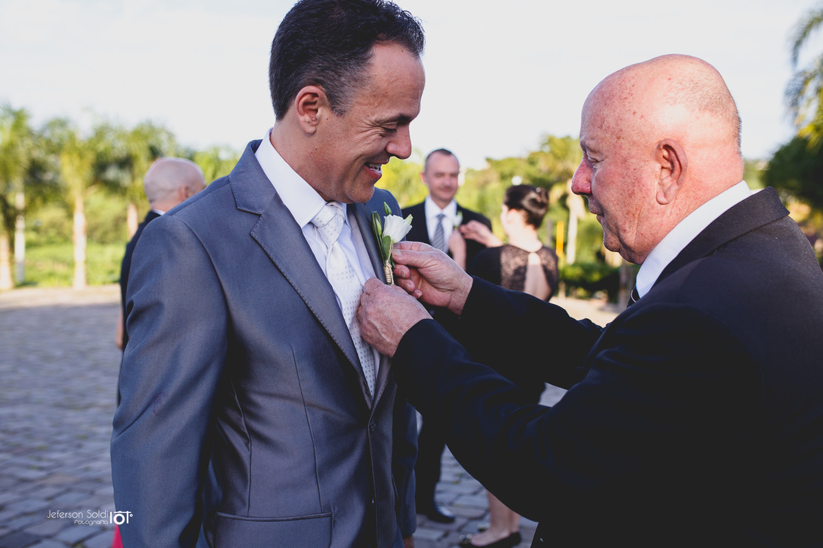 Pai do noivo colocando o cravo na lapela do terno.