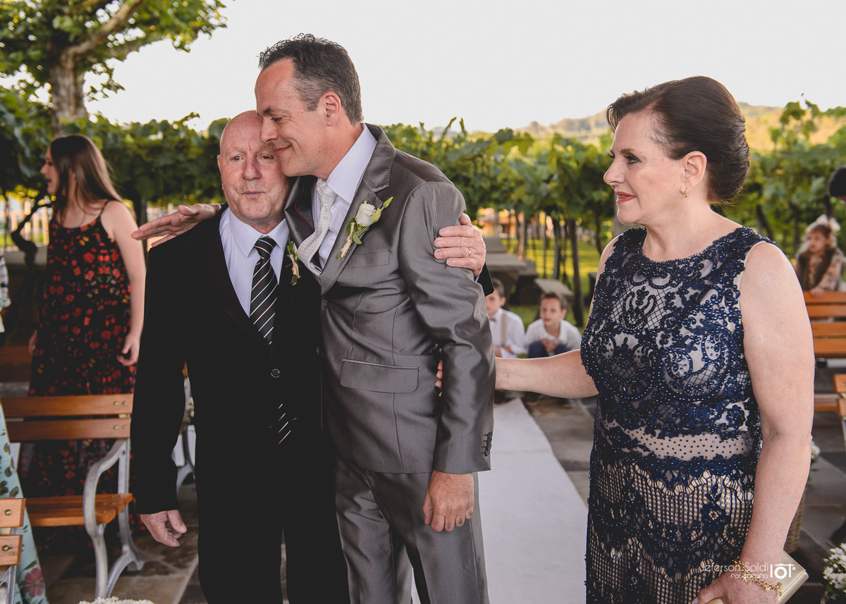 Noivo abraçando seus pais.