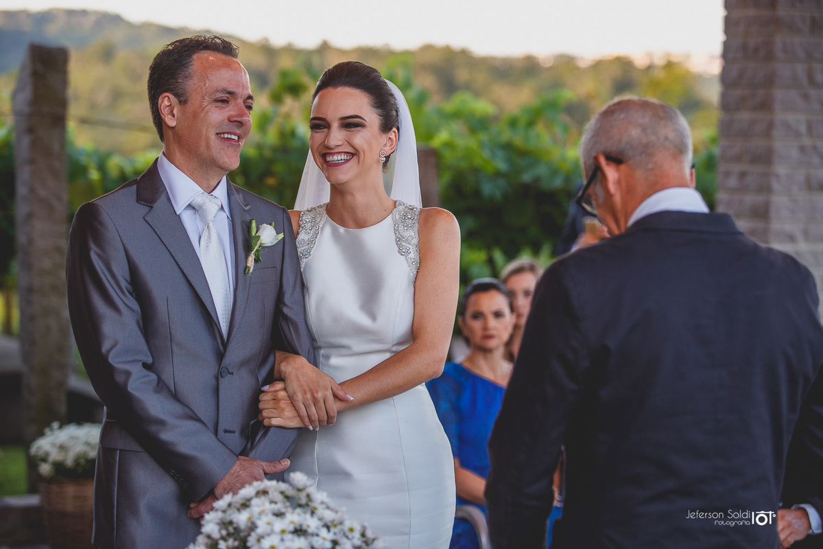 Noivos sorrindo diante do juíz de paz.