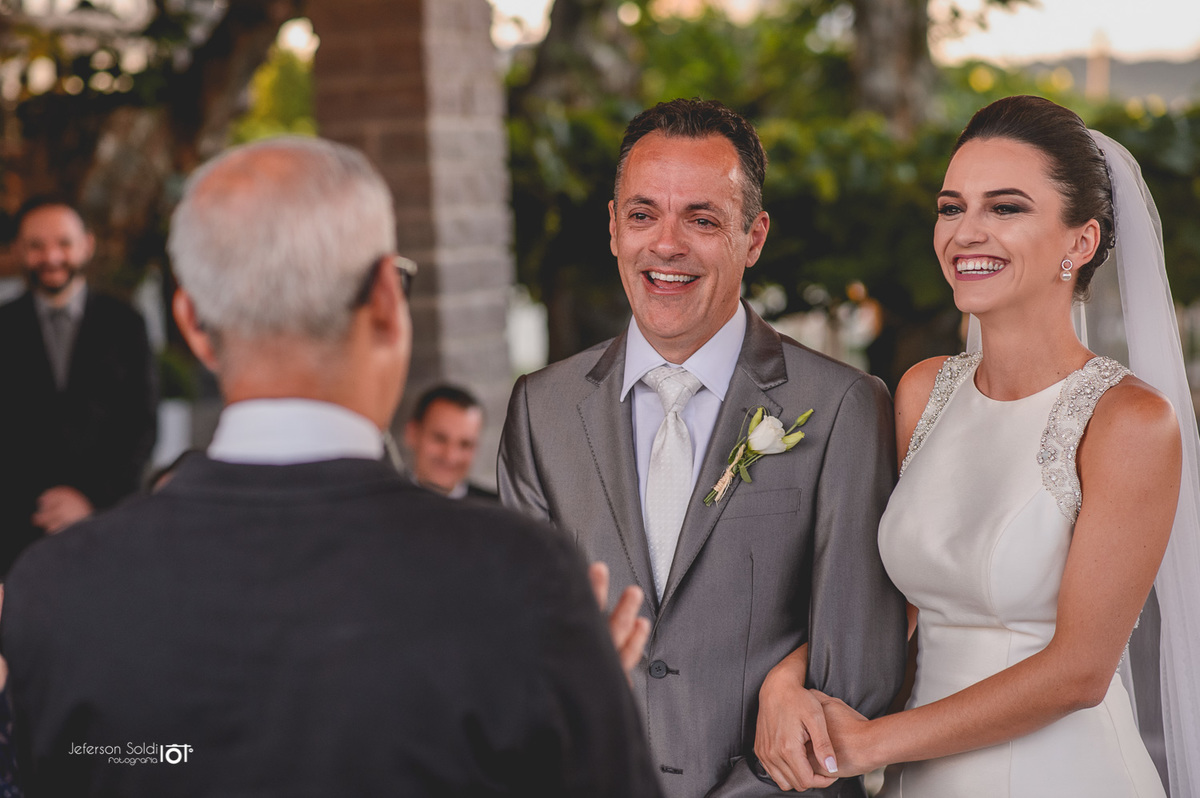 Noiva e noivo sorrindo diante do juíz de paz.