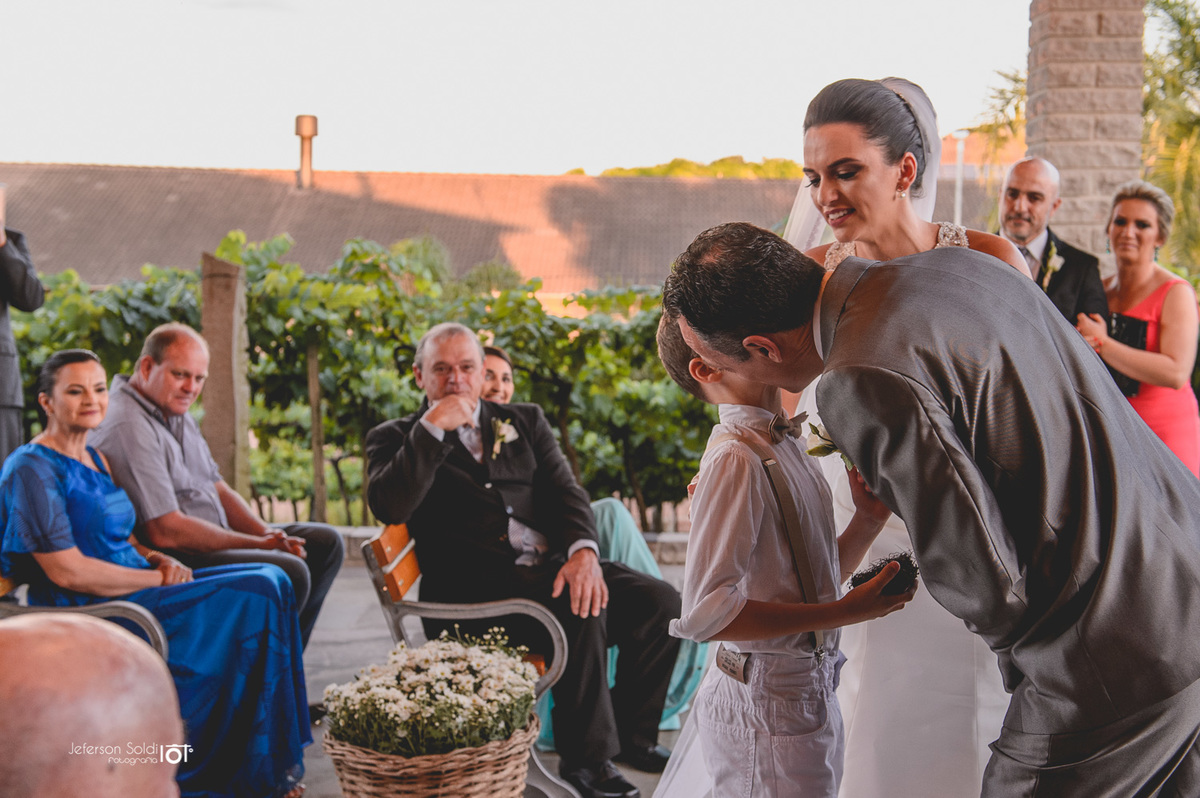 Pai beija o filho ao receber as aliaças.