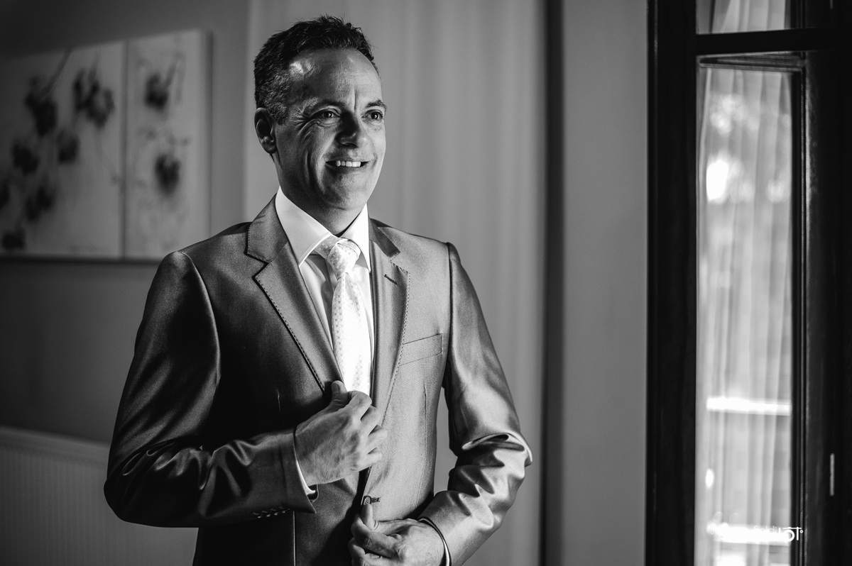 Noivo ajeitando o terno em frente aoa espelho.