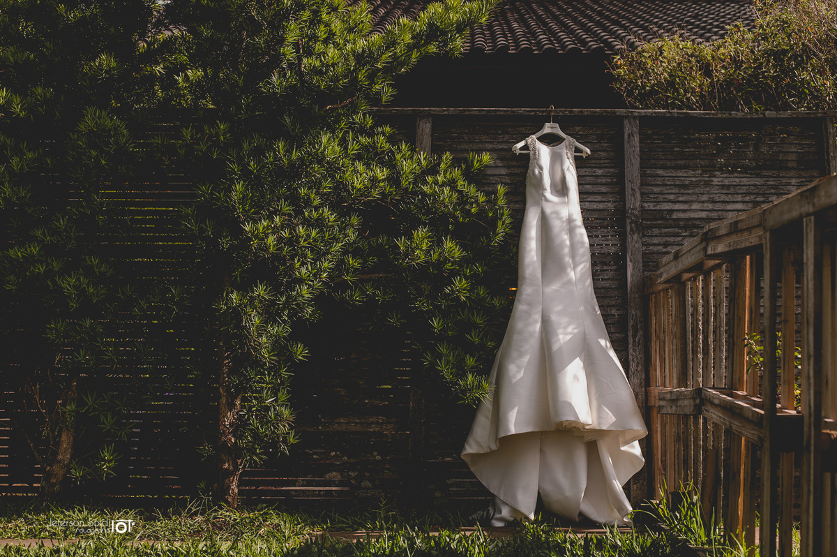 Vestido da noiva pendurado na divisória  da área  externa da estética.