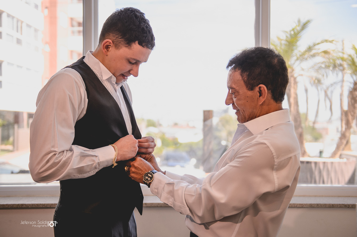 Pai do noivo ajudando a colocar o terno.