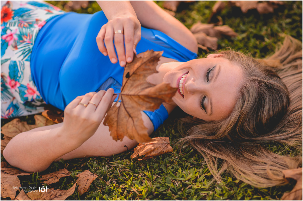 Elisa deitada na grama segurando uma folha seca de parreira