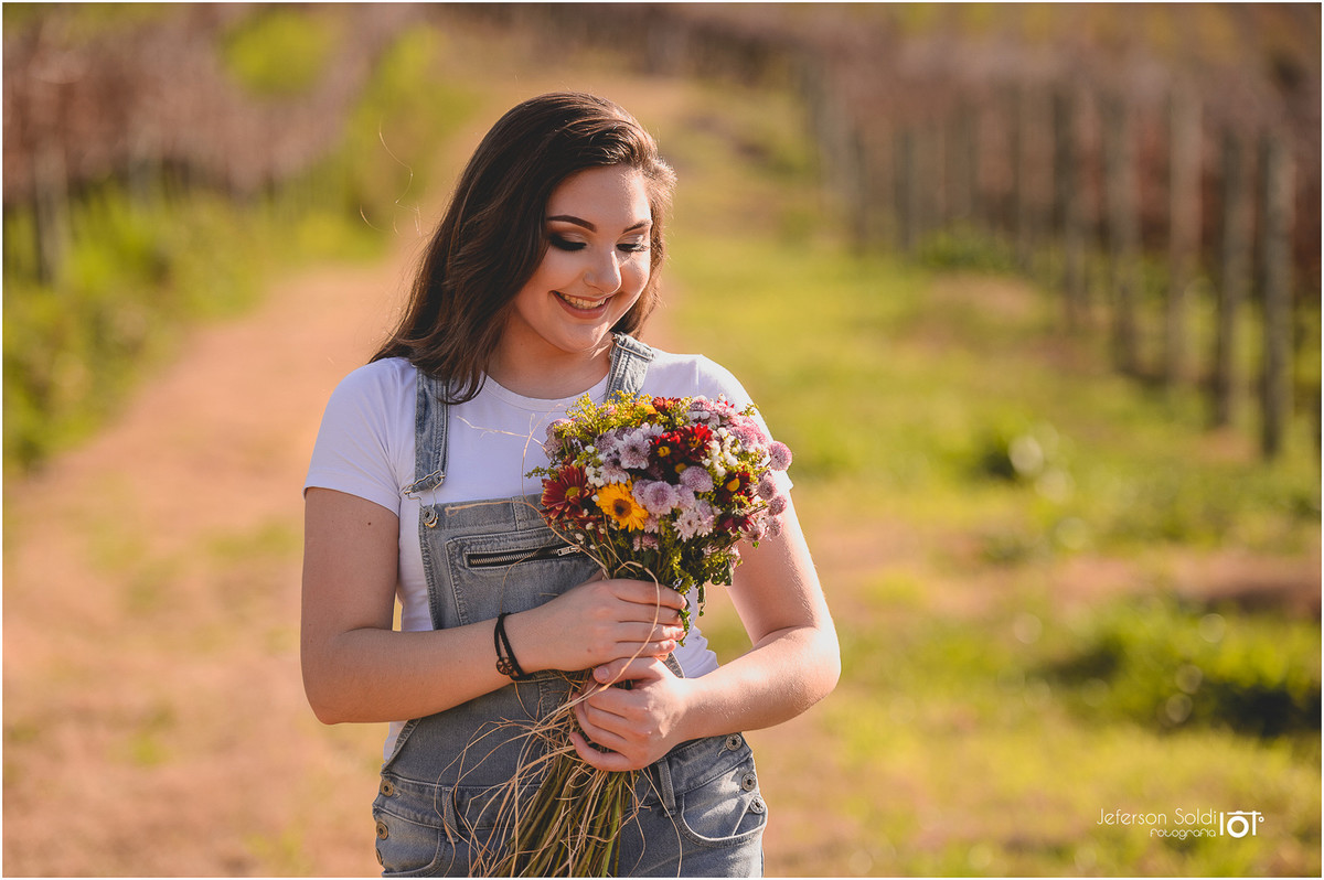 Julia segurando um buquè de flores em meio aos parreirais