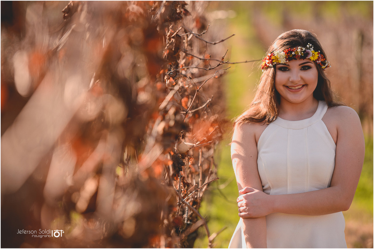 Julia com uma coroa de flores silvestre ao lado dos parreirais secos no outono vale dos vinhedos