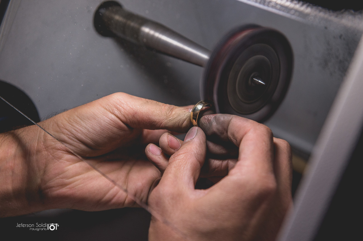 Noivo pulindo a aliança que está fabricando.