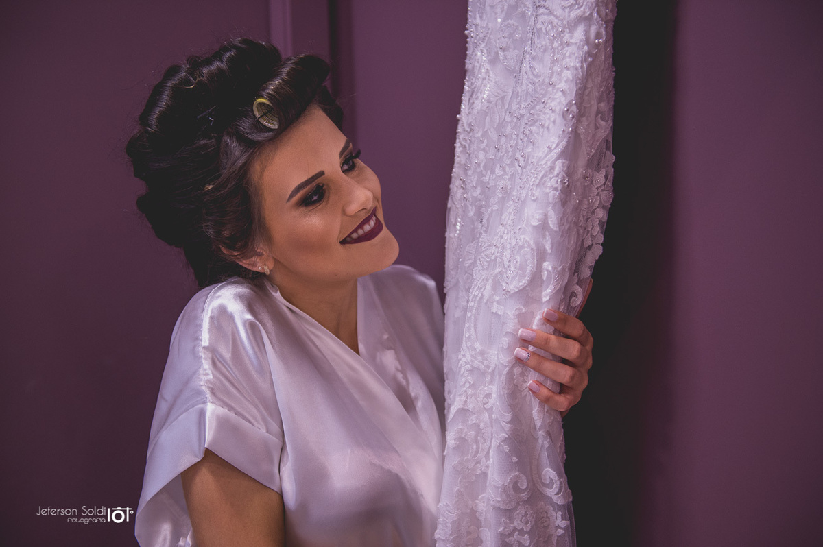 A noiva abraçando o seu vestido e admirando cada detalhe nele.