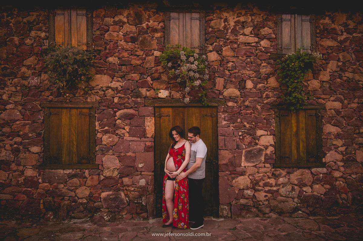 papais posando para foto em frente a uma linda casa de pedras