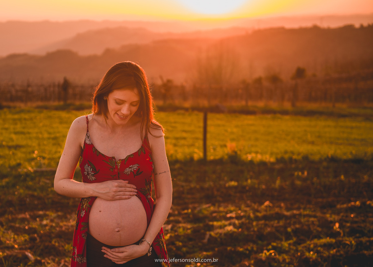 mamãe gestante abraçando a barriga em um lindo final de tarde