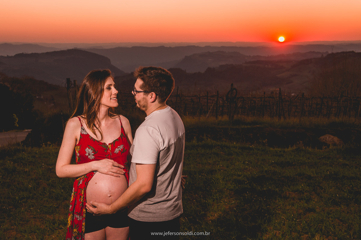 Casal de gravidos se olhando e papai abraçando a barriga da mamãe e ao fundo o sol se pondo, espetacular.