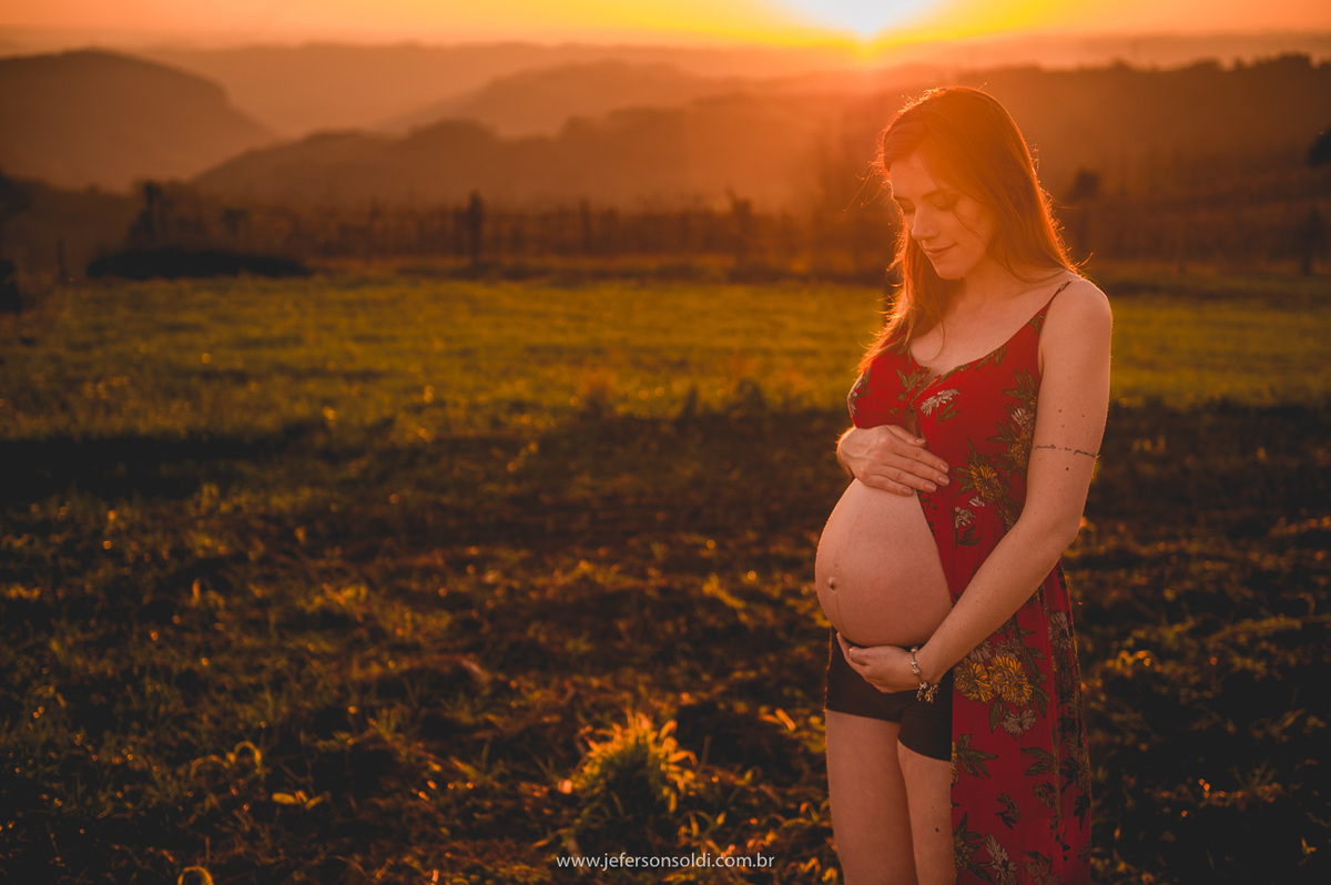 Gestante pousando para foto contemplando a linda barriga e um final de tarde encantador