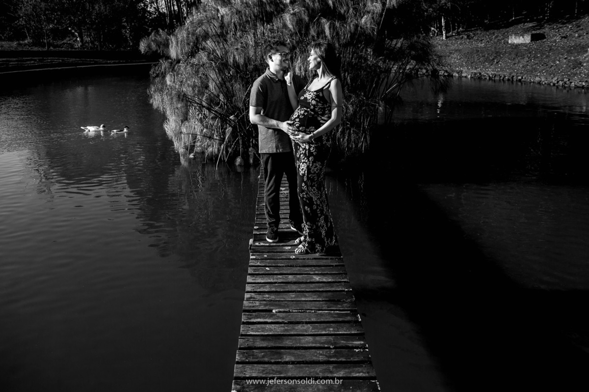 o casal que está gravido em cima de uma pontezinha em uma foto preto e branco