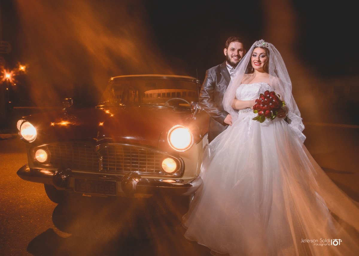 Noivos posando junto ao carro que conduziu a noiva