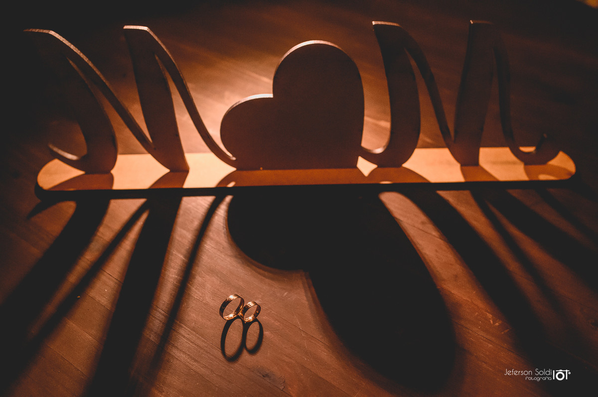Foto das alianças junto as letras iniciais dos nomes do casal