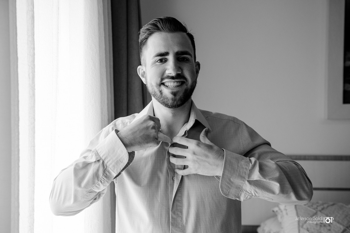 Noivo vestindo a camisa para o casamento