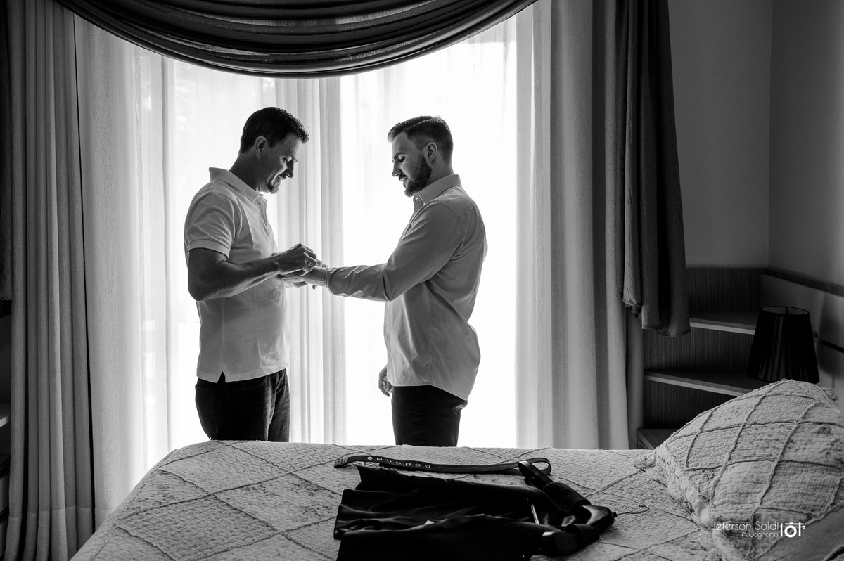 Pai do noivo ajudando a abotoar a camisa