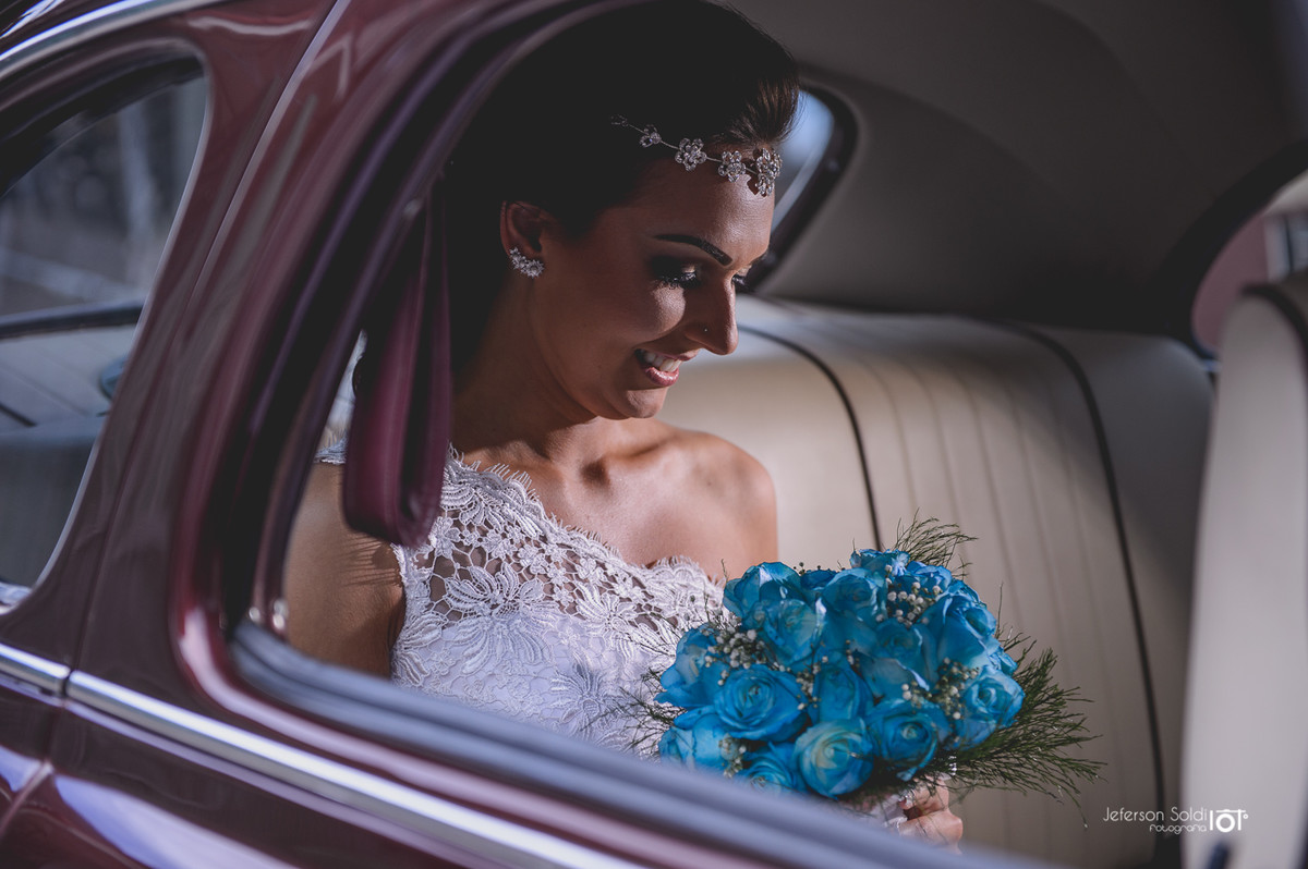 Noiva dentro do carro olhando para o bouquet.