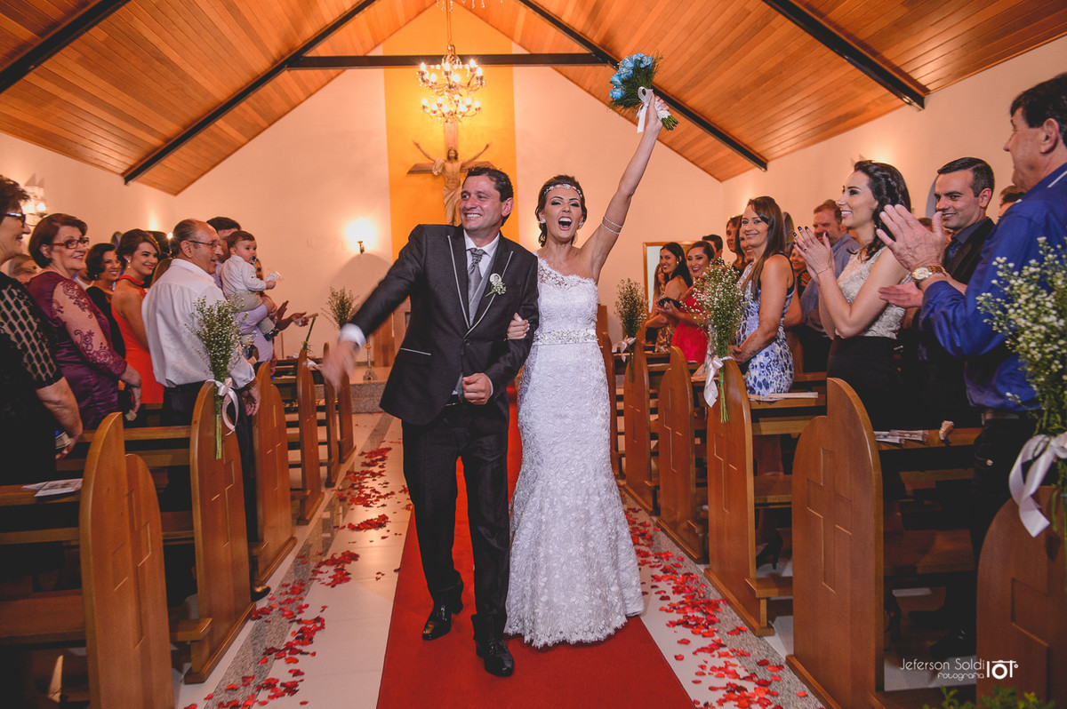 Noivos deixando o altar e noiva levantando o bouquet.