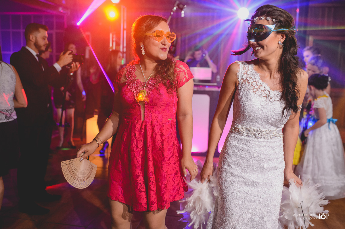 Noiva e convidada dançando com mascaras.