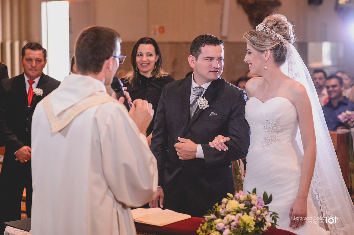 Noivos no altar recebendo a benção do padre.