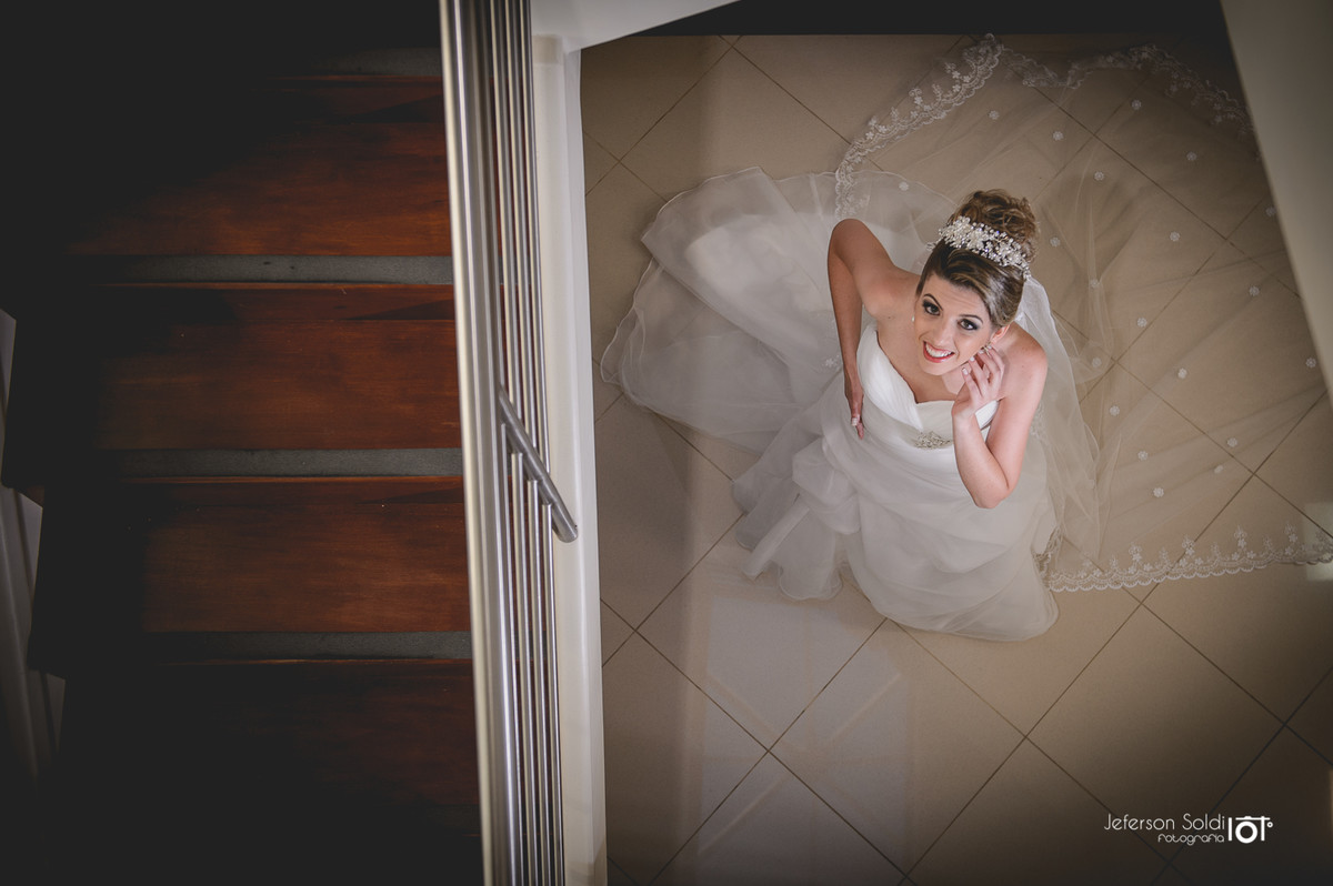 Noiva pronta sendo fotografada do alto da escada.