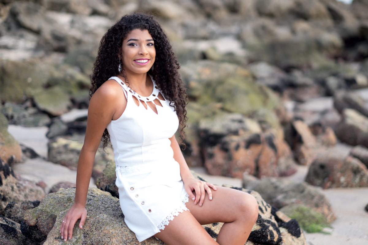 Ensaio debutante Ana Flávia sentada nas pedras na Praia das Conchas Guarujá Alice Casaes Fotografia