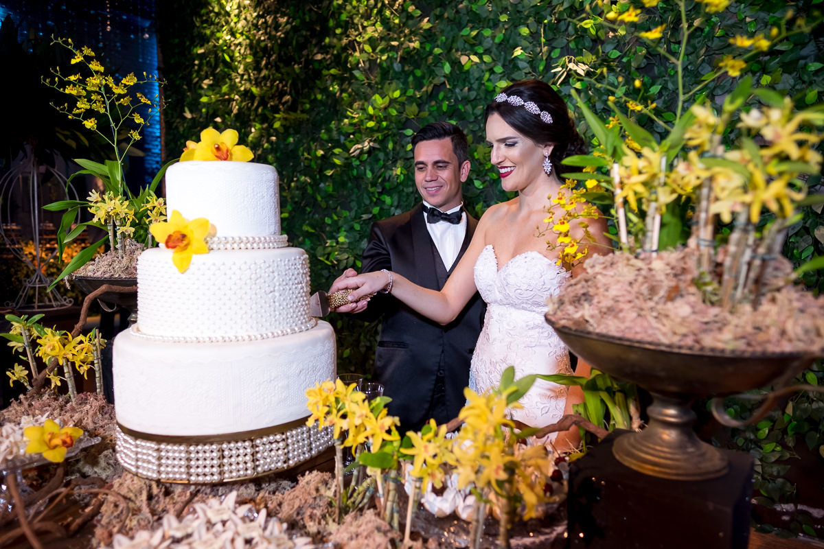 noivos cortando o bolo em espaço atmosphera com decoracao de flora nativa