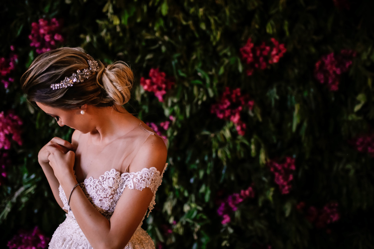 noiva olhando na diagonal com flores rosas atras
