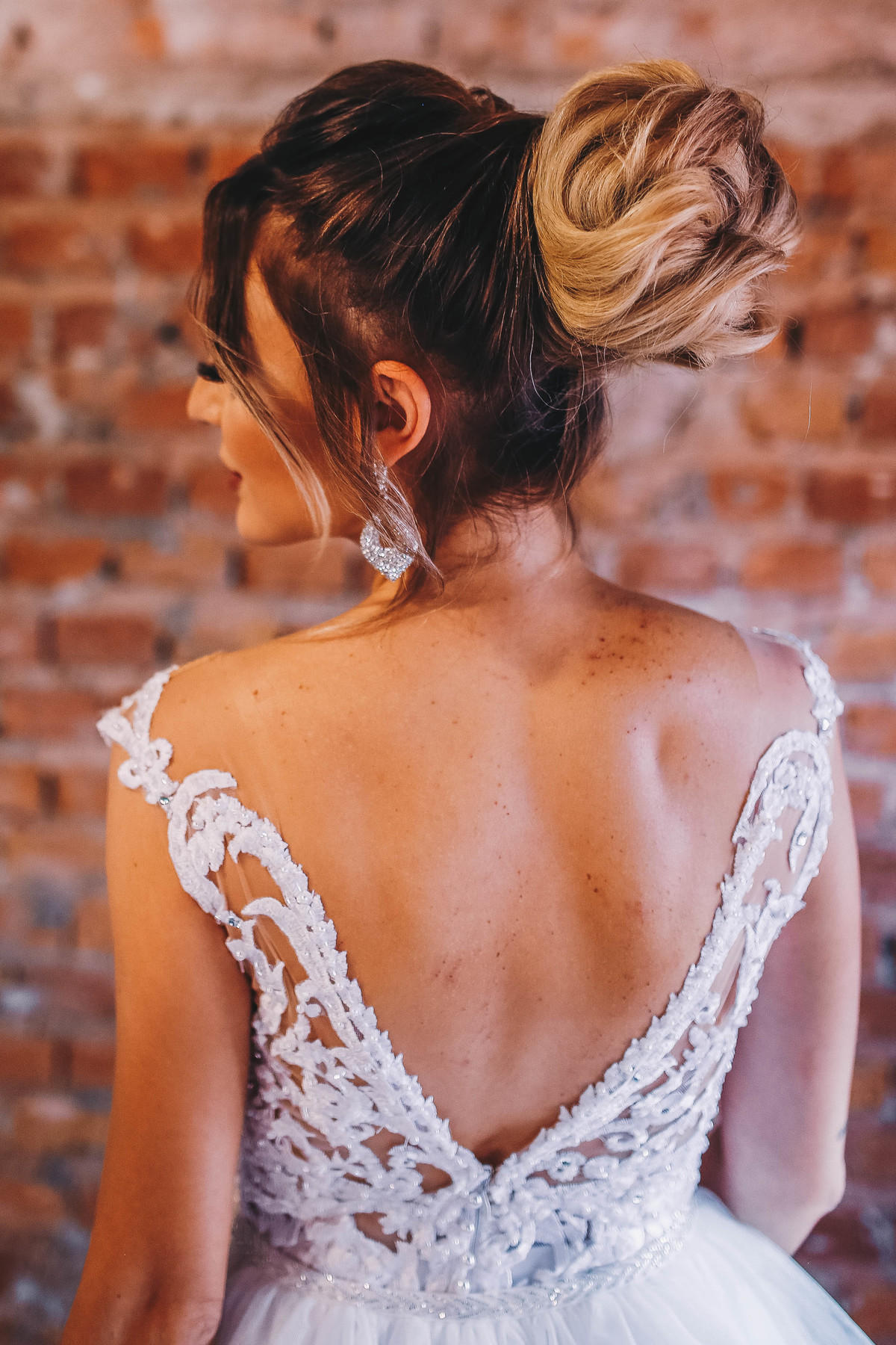 costas de uma mulher loira em frente a parede de tijolos