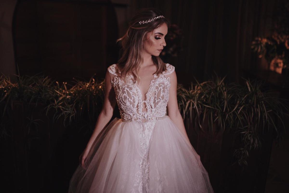 mulher loira de vestido branco em frente a flores