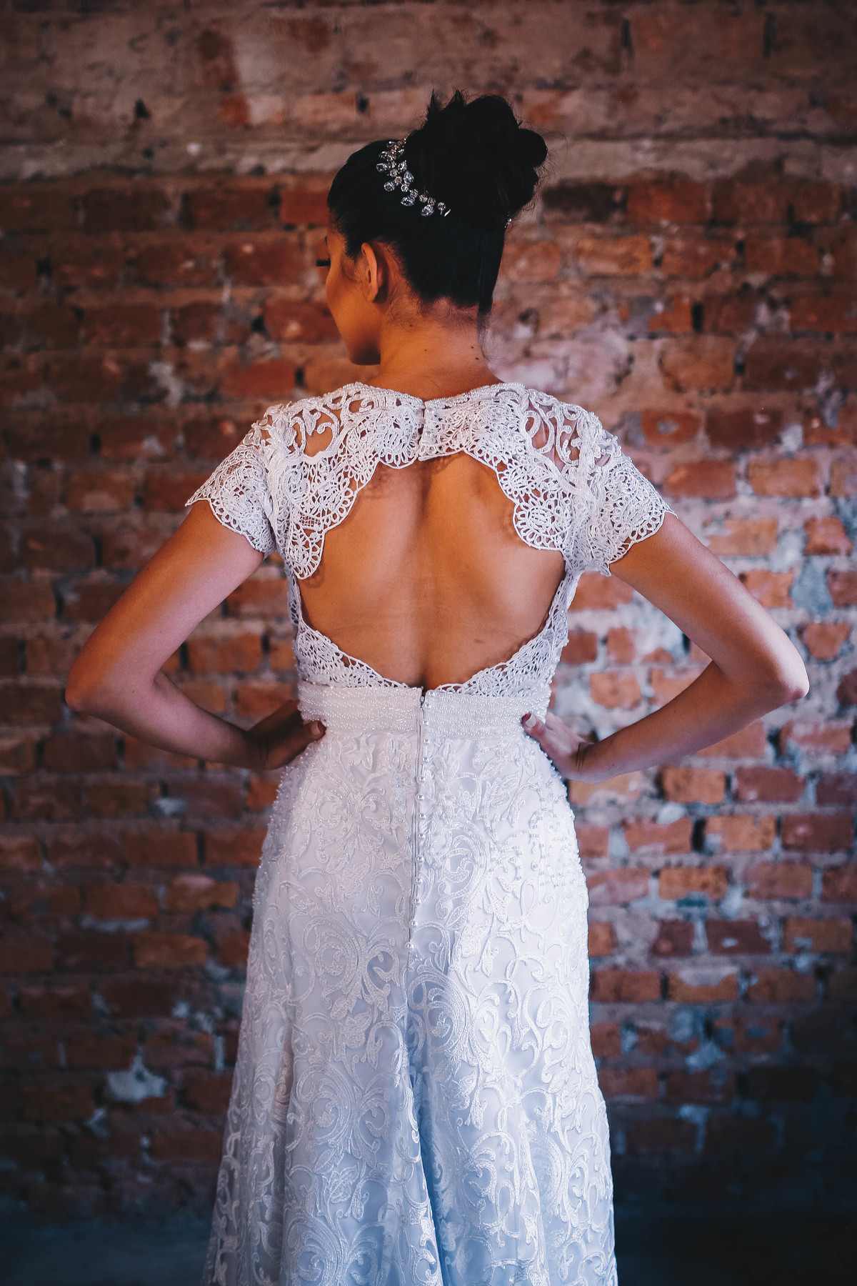 costas de noiva em frente a parede de tijolos 