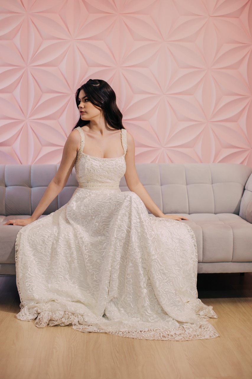 mulher de vestido branco sentada num sofa