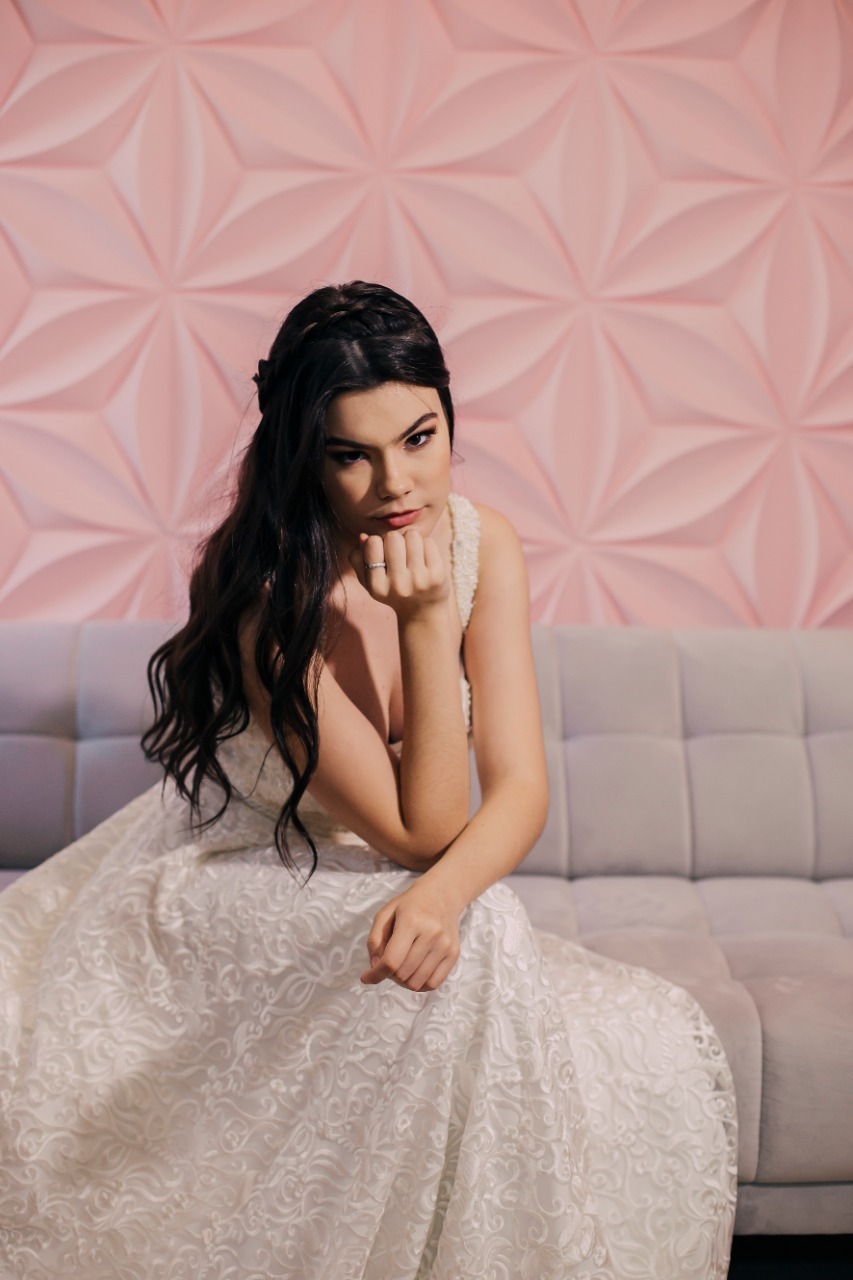 moça de cabelo preto sentado em sofá cinza 