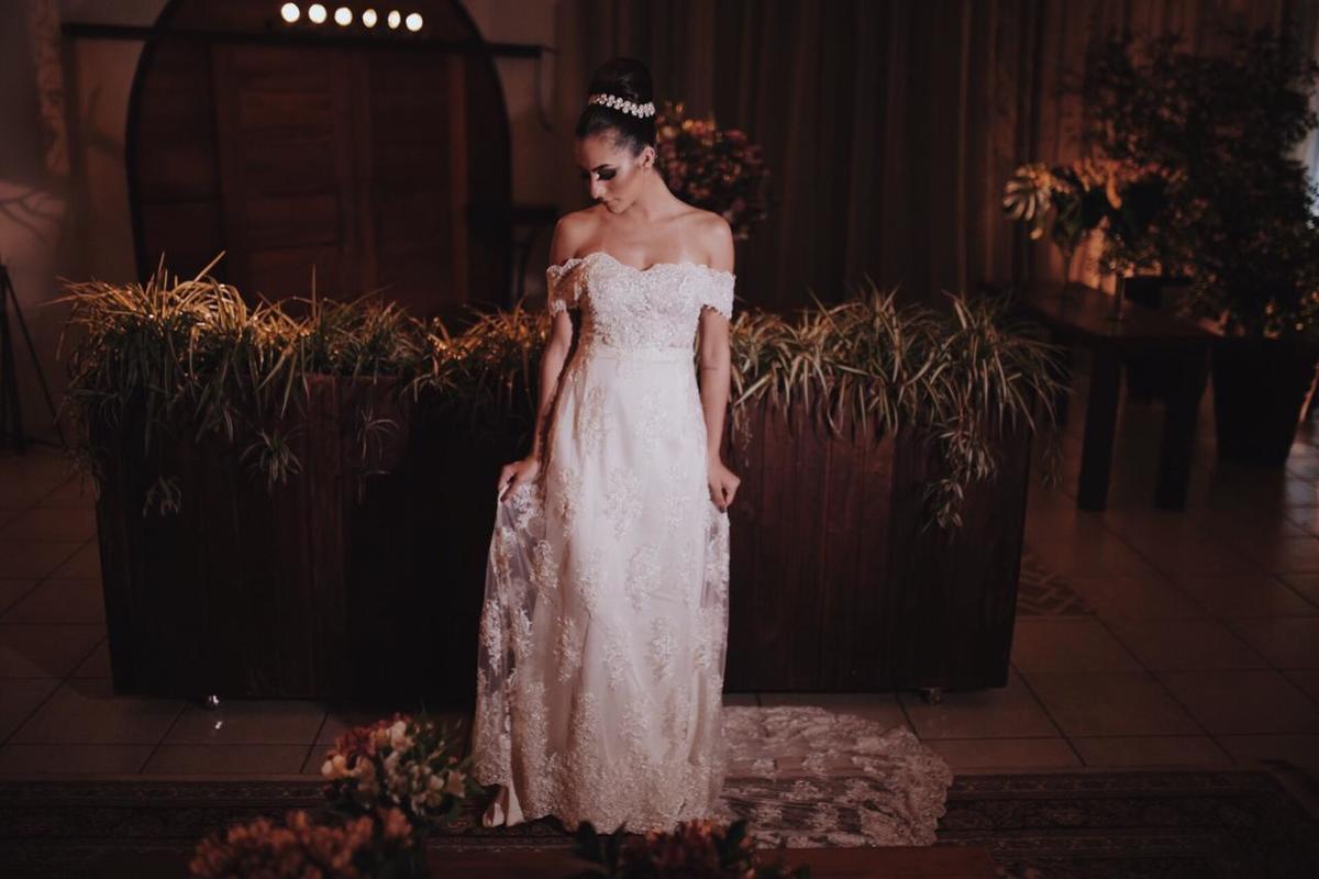 mulher posando de vestido branco em frente a mato artificial