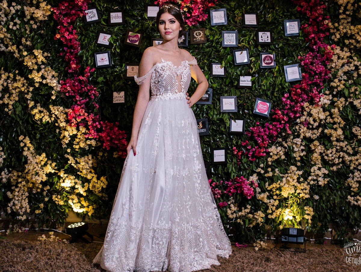 mulher de vestido branco em frente a flores rosas