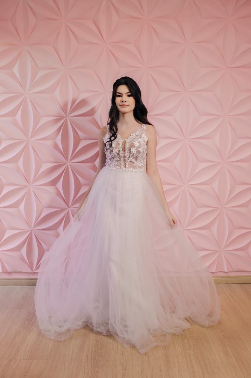 mulher de vestido branco em frente a parede rosa