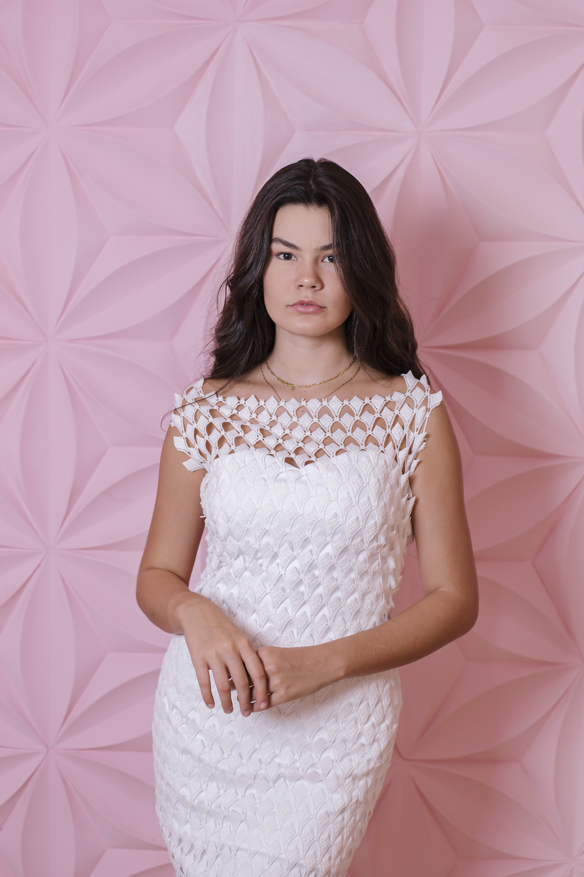 mulher de cabelo castanho em frente  a parede rosa