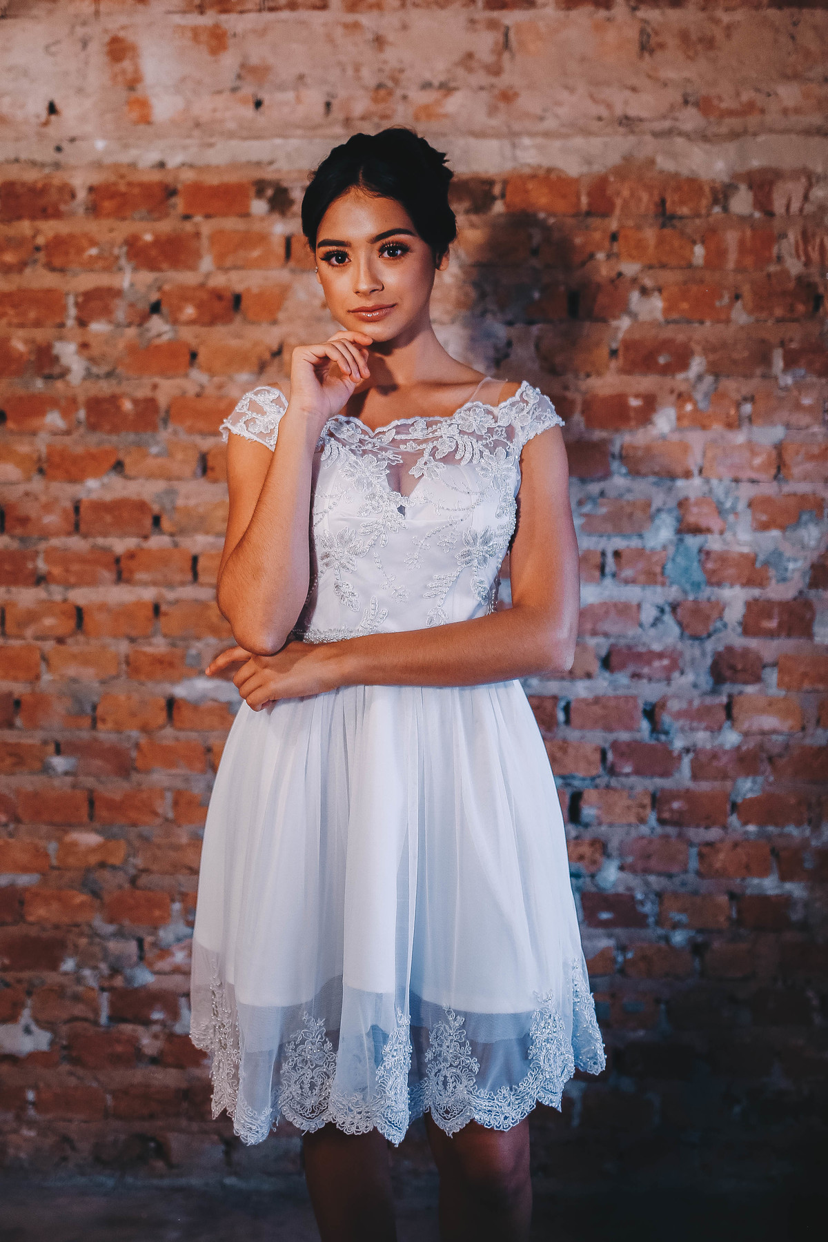 mulher com mão no rosto em frente a parede de tijolos