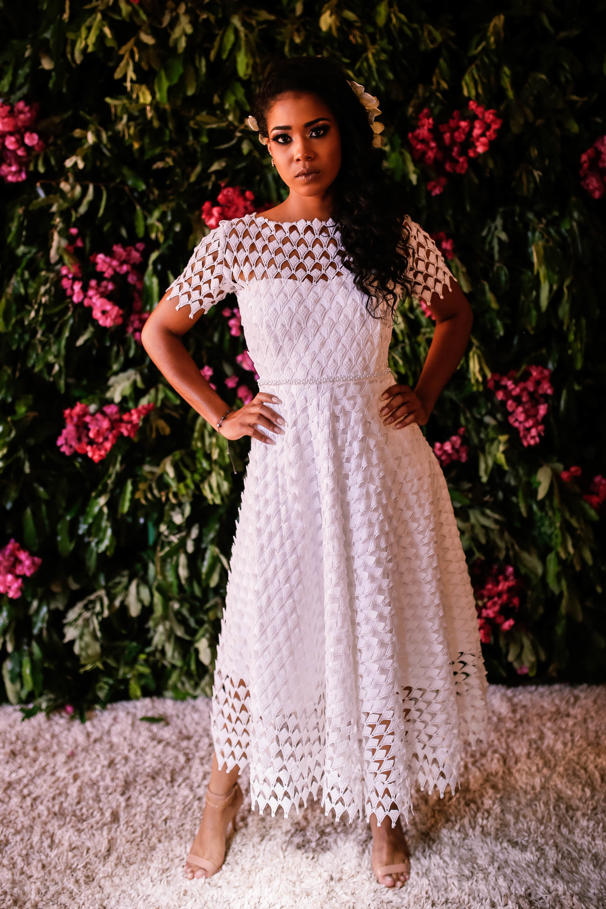 mulher com mão na cintura em frente a flores