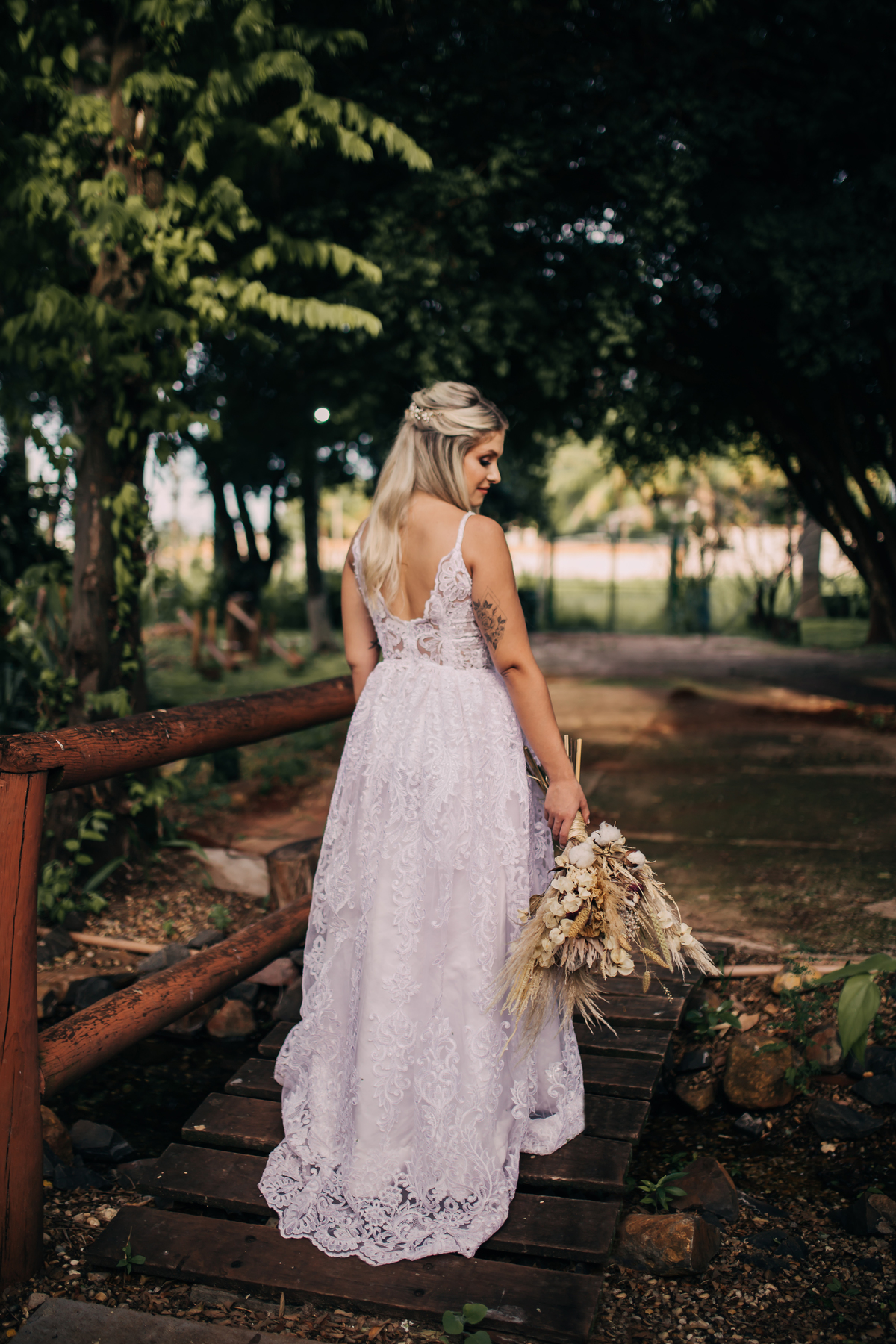 mulher de vestido branco de costas em local com arvores 