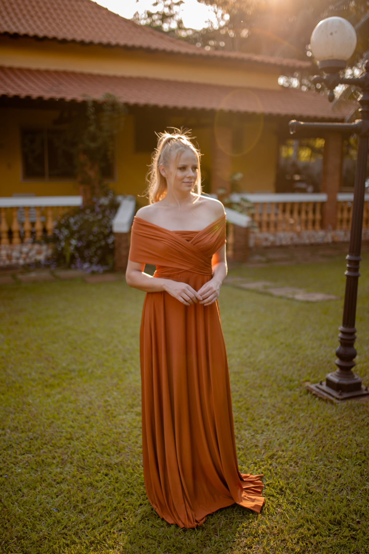 mulher loira de vestido laranja em um quintal de casa